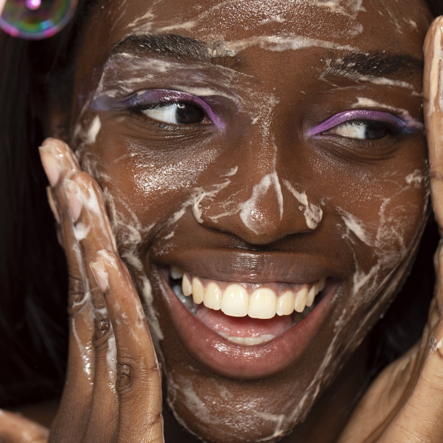 Smiling woman washes her face with gentle foaming Pink Cloud Cleanser